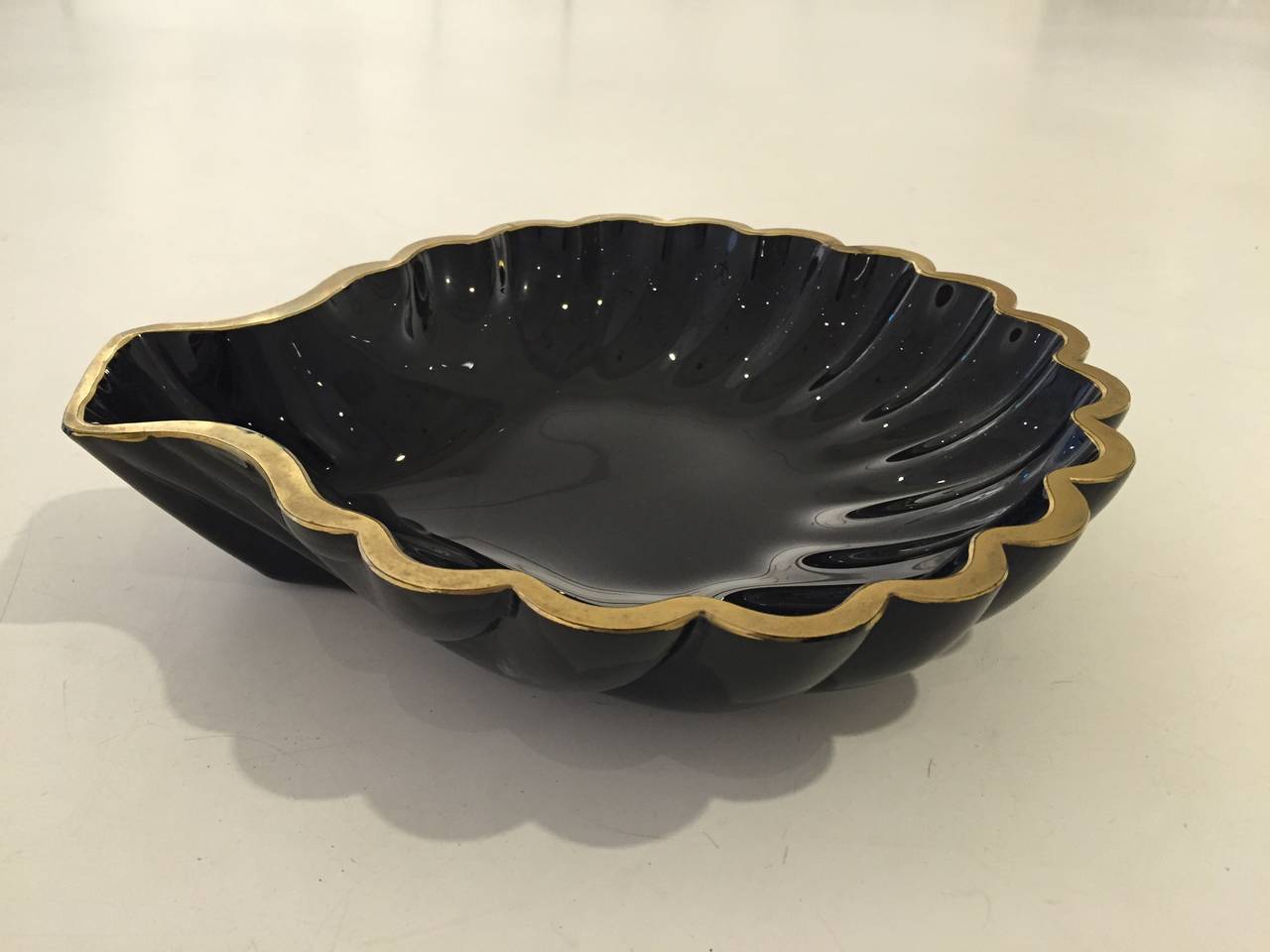 Shining black opaque Murano glass scallop shell bowl with a hand-applied matte gilt edge. By Cenedese, 1950s, retaining original retailer's paper label on bottom.
