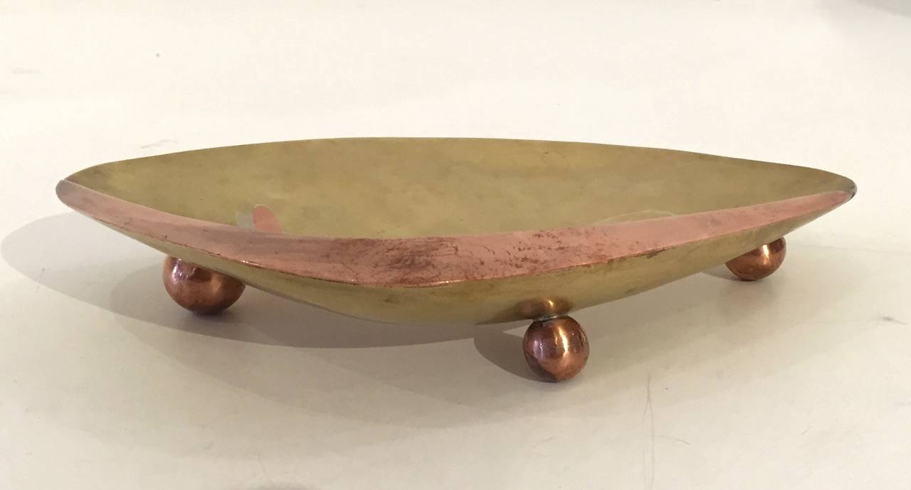 Hand-forged bronze low bowl in the form of a clamshell raised on three brass ball feet and inlaid with a shrimp in copper and sterling silver. By Los Castillo, 1950s, signed on underside.