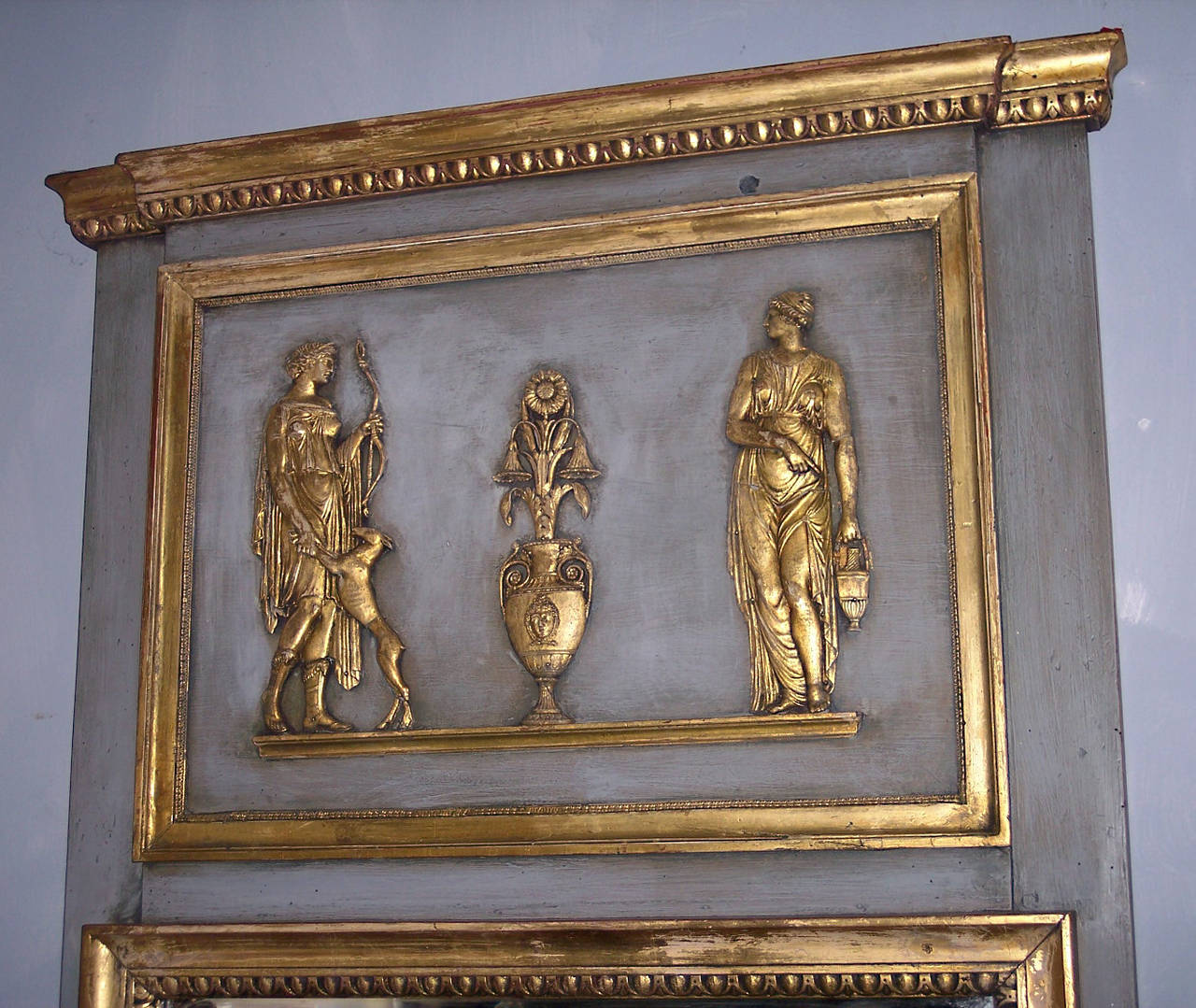 A 19th century French trumeau mirror. Gilded and patinated, richly decorated with Classical Greek carved figurative reliefs.