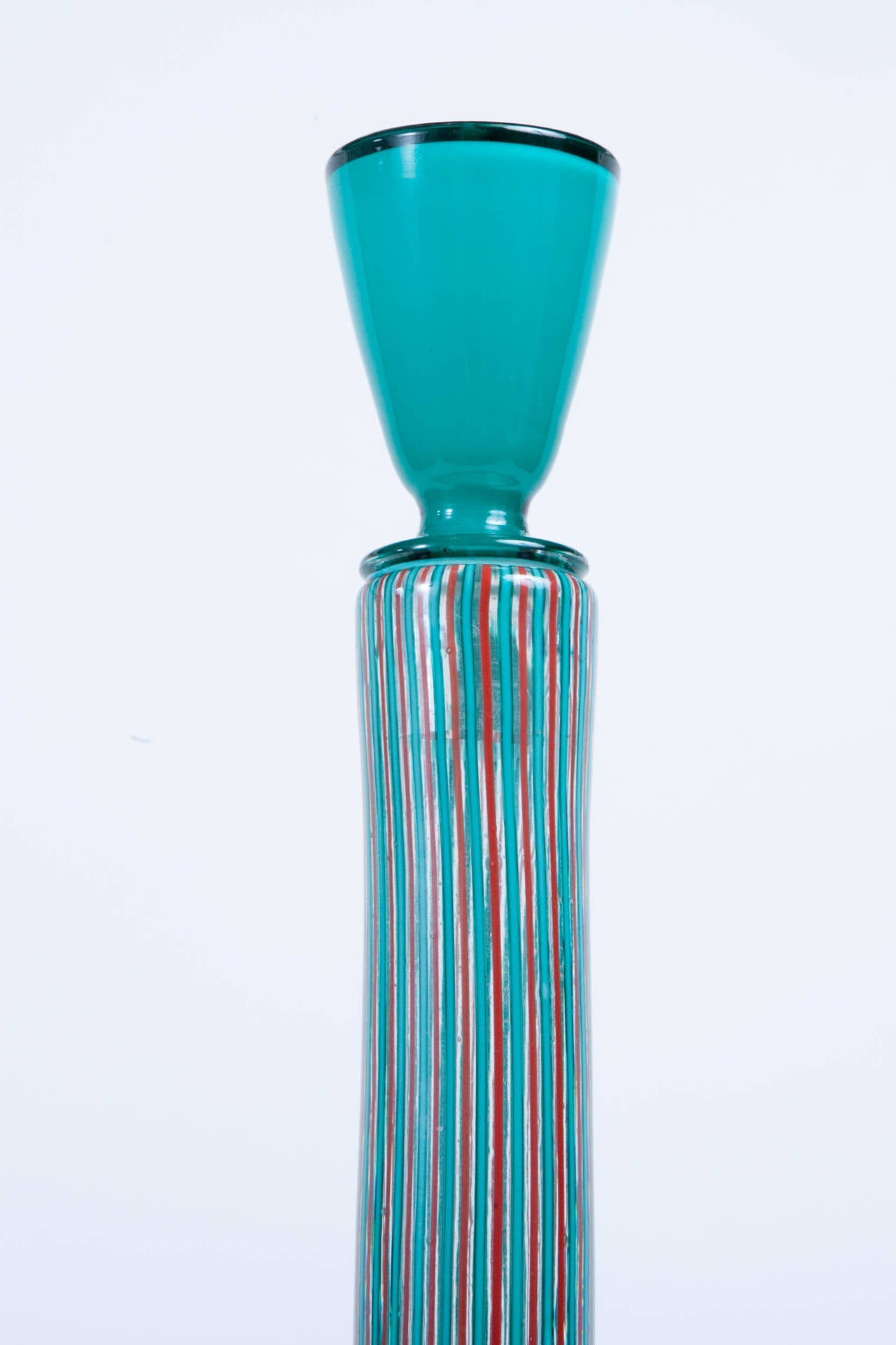 Tall vertically stripped Paolo Venini bottle with red, turquoise and clear glass and a turquoise glass stopper. Paper label at base.