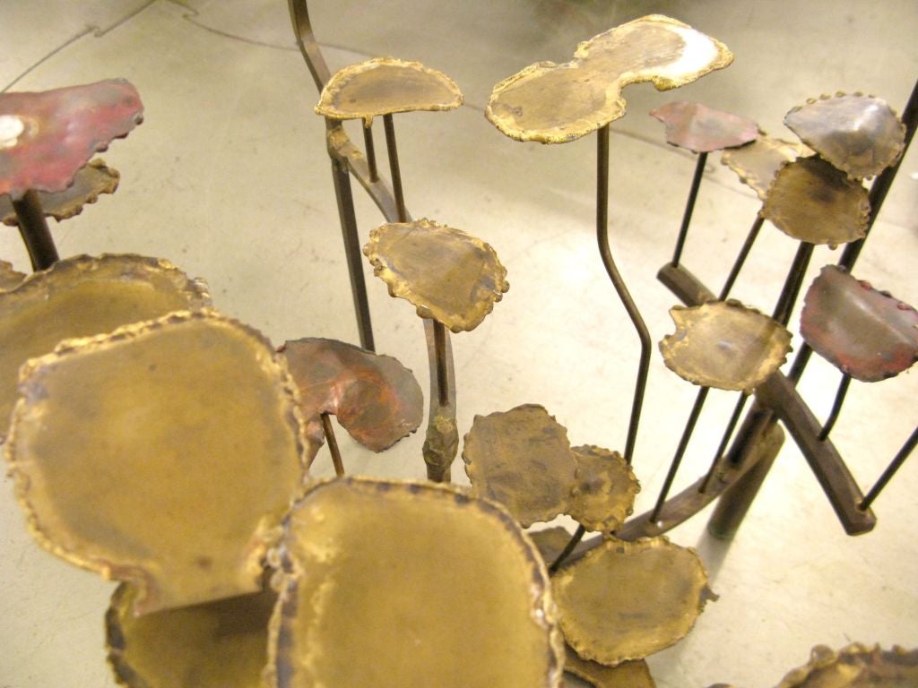 Figural brass and glass side table with an organic lilypad design.