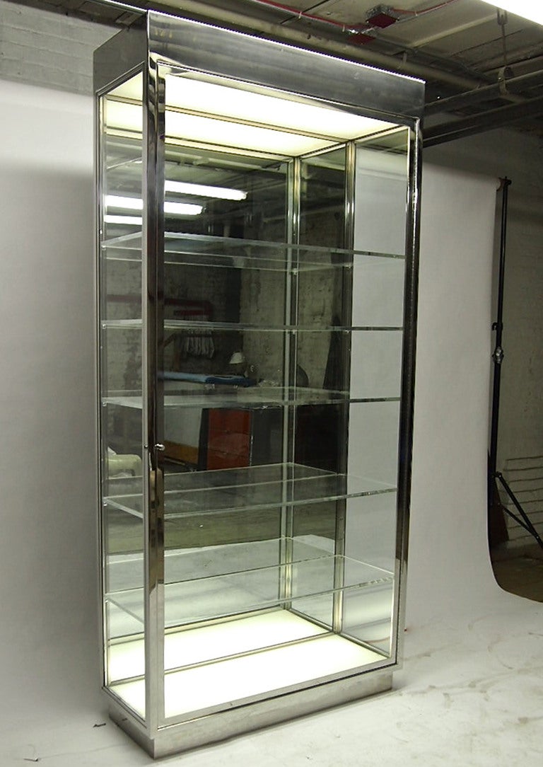 Display case that has a mirrored back, five adjustable shelves and diffused lights on the top and bottom as shown in the lead photo. The exterior is solid polished steel with clear glass on each side and the door. Photo five shows a simple, solid