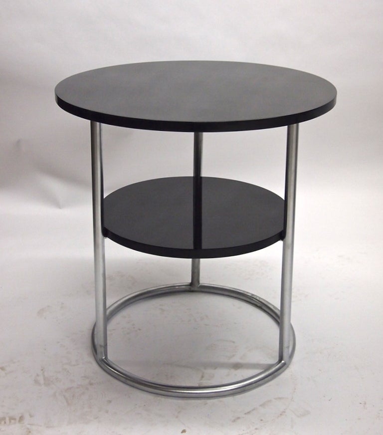 Pair of round side tables with a brushed tubular steel frame that supports a, 16 inch diameter, lower shelf and larger top both in black lacquer. 
Six available.