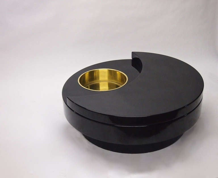 Coffee table by Willy Rizzo in black lacquer with a circular brass planter/holder/ice tray and a crescent shaped upper level. The base is fixed and the body rotates.