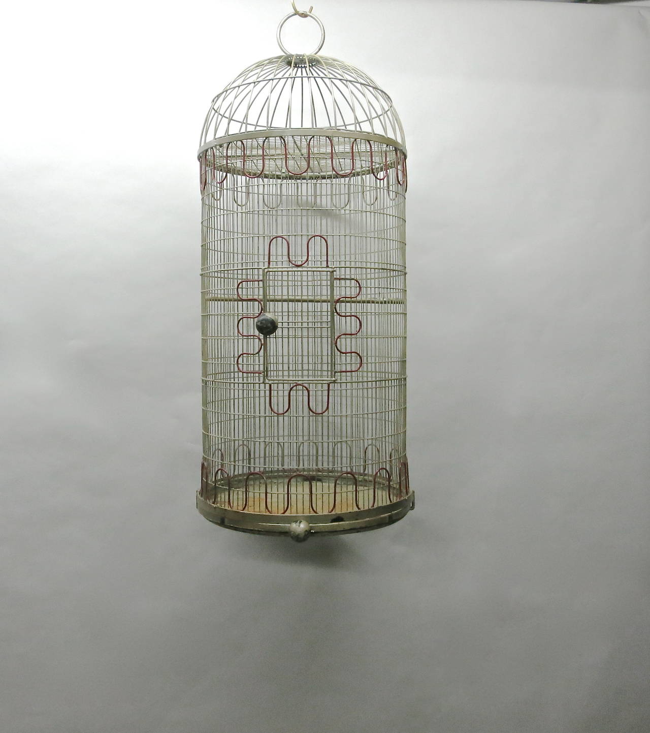 Bird Cage in original condition made of enameled metal with red detail of inverted arches in three places, just above the tray around the door and just bellow the dome top. Both the dome top and the tray are removable. The door and the bottom tray