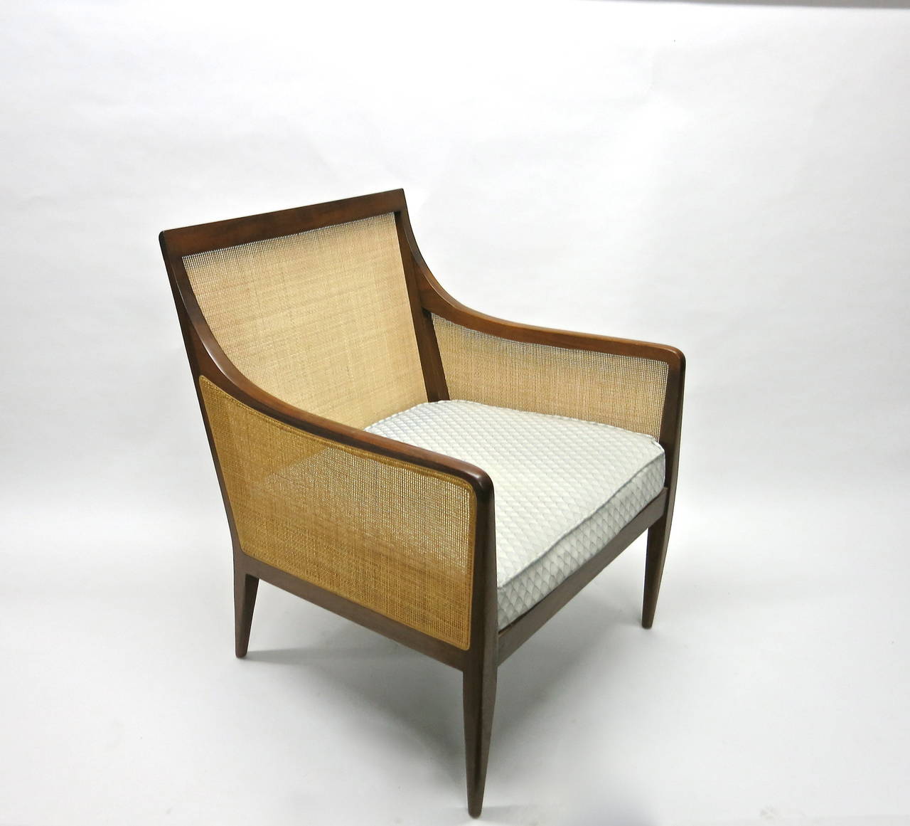 Chair in solid walnut with caned back and sides designed by Kipp Stewart for Directional. The caning and wood are all in excellent condition; the seat cushion is attached to the chair and the back cushion is loose for optional use. Both cushions are
