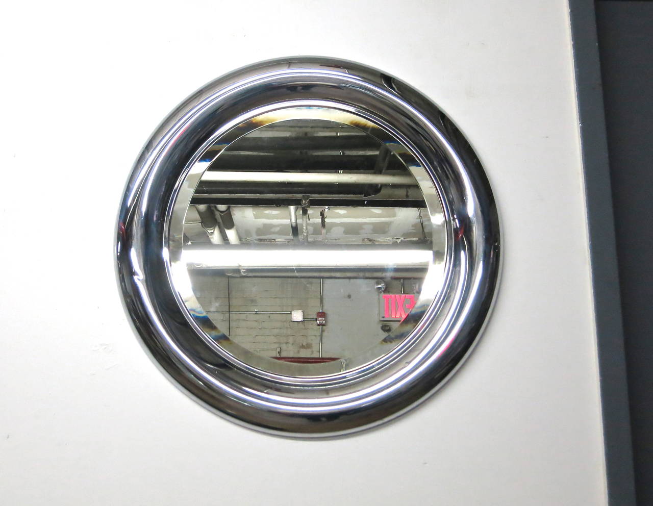 Round beveled edge mirror has a convex polished steel frame with manufactures labels on the back.