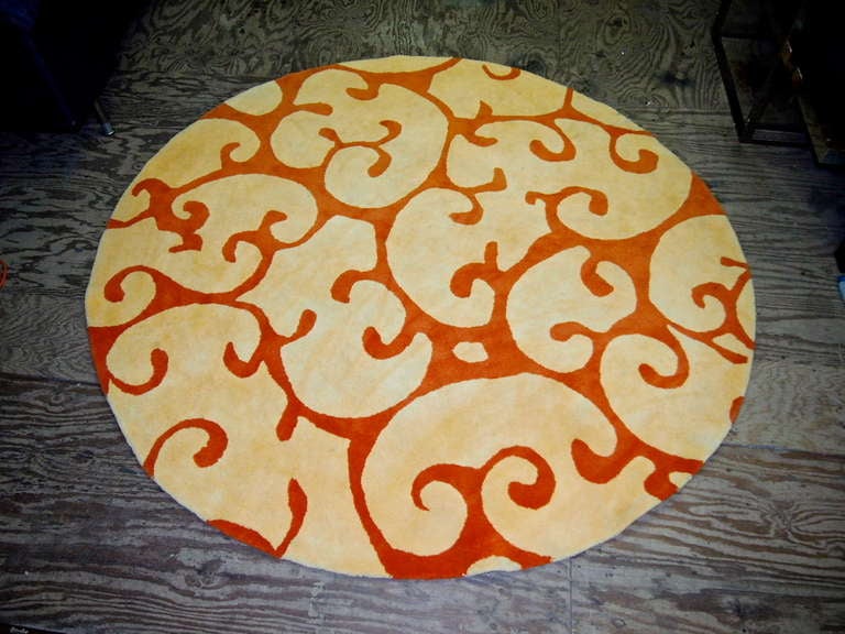 Round rug in wool with an orange swirl-vine design.