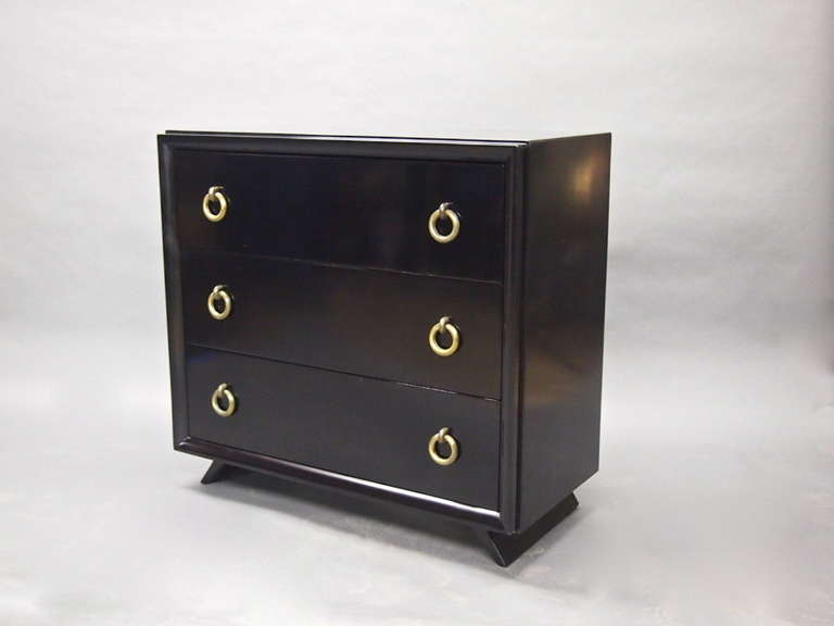 Pair of black lacquered cabinets each with three drawers and solid brass pulls all resting on a base of two angled legs.