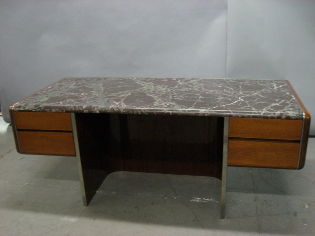 Executive desk in mahogany with bull-nose marble top trimmed with nickel supported by a stainless steel base.
