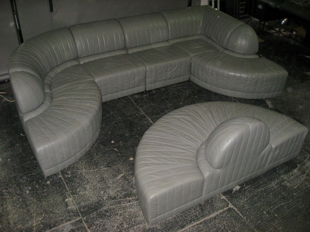 SECTIONAL SOFA IN GREY LEATHER COMPRISED OF SEVEN PIECES THAT FORM MANY SHAPES