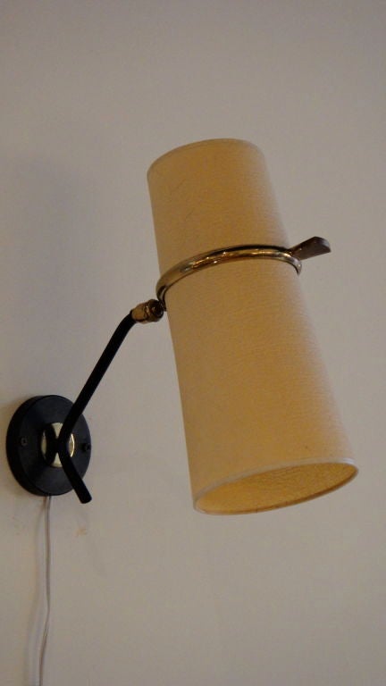 Set of sconces have a top and bottom shade, each with a single socket. The frame is tubular black enameled steel with a brass ring supporting the shades. The sconce articulates at the brass ring.