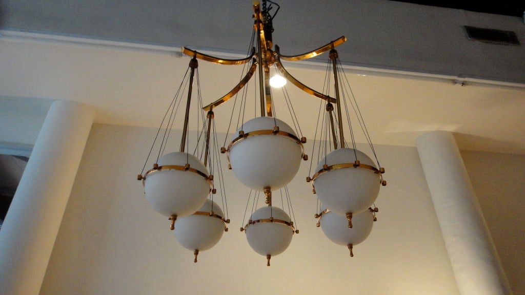 Ceiling fixture by Stilnovo in solid brass with six floating globes in white opaque, cased glass suspended on wire supports.