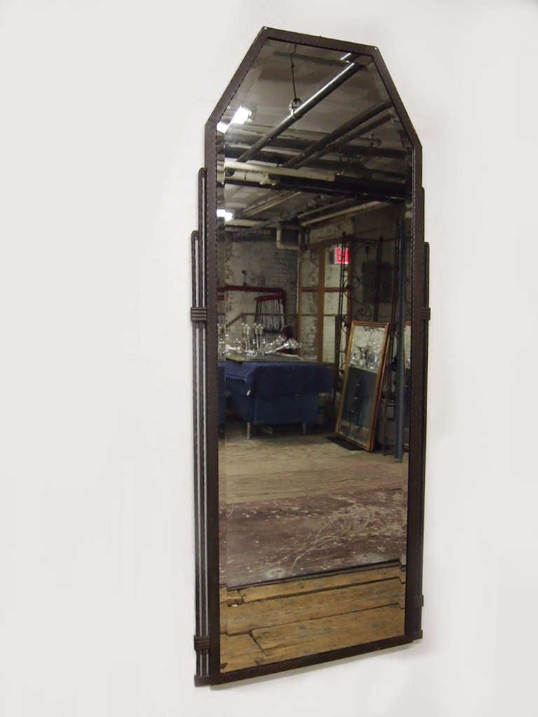 Mirror with bevelled edge is set in a hand hammered wrought iron frame with graduating detail that angles in at the top. Made in France in the early 1900's