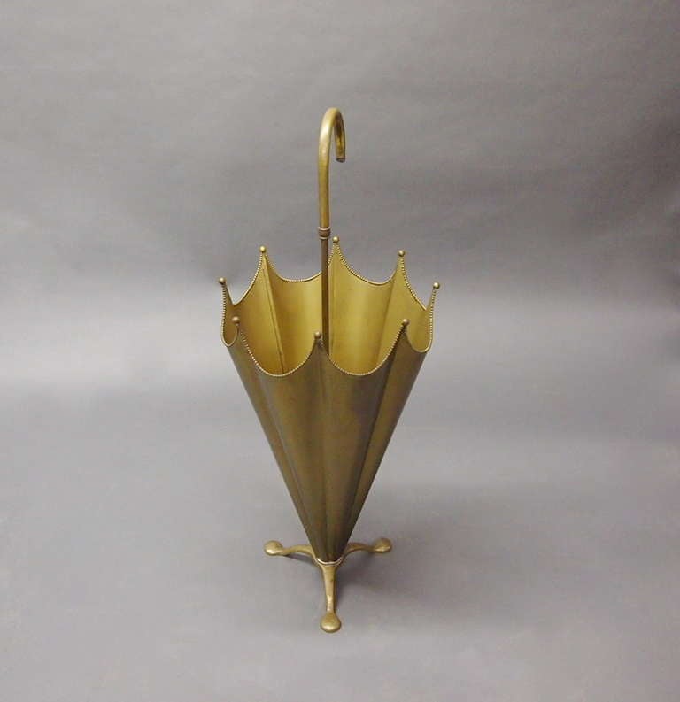 Umbrella stand in patinated brass in the form of an open umbrella with beaded detail sitting on a brass tripod base is what distinguishes this from other later models