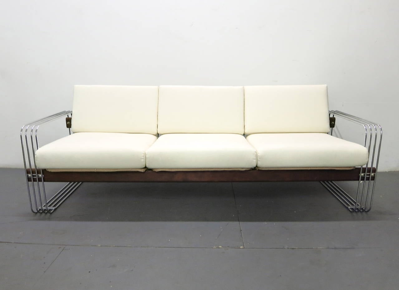 Sofa has a metal rod frame at each end with a wood stretcher that supports three-seat and back pillows in newly upholstered white canvas.
Designed by Robert Haussmann for Stendig in the 1960s.