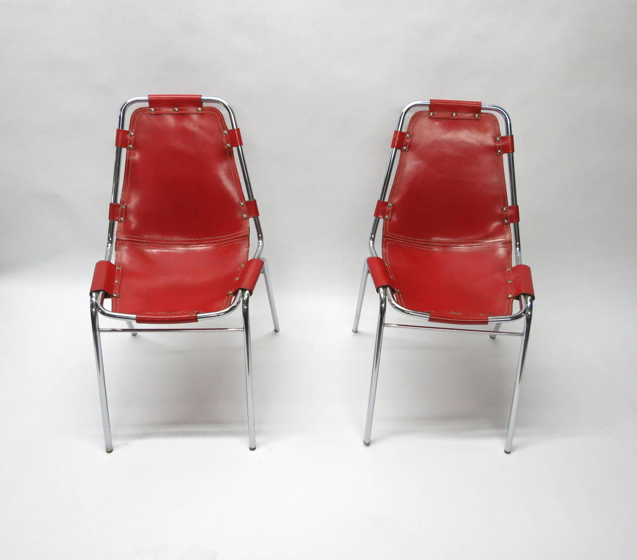 *SUMMER SALE*
Set of four stackable dining chairs in original red leather. The seat and back are stitched together and riveted to the chrome frame. The chairs are in the original condition with normal wear to the leather and very few missing