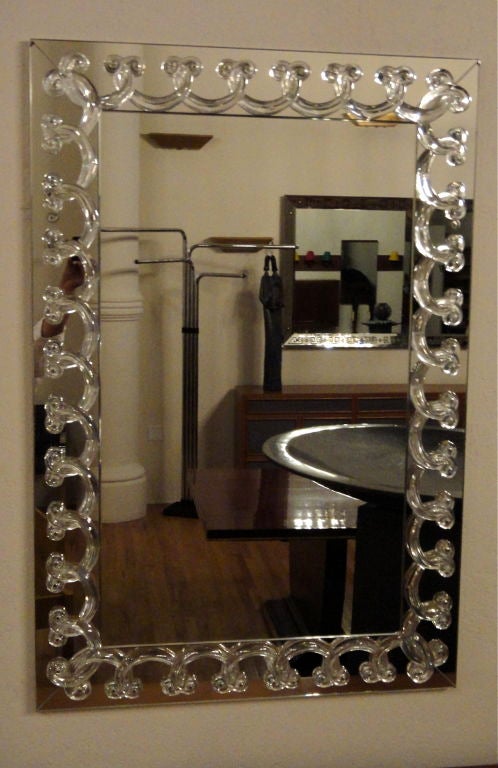 Mirror by Rene Lalique; A 70's production of a 1930's design. The borders are slightly set back and mitered at the corners. Also consists of a decorative, interlocking and overlapping crystal detail.