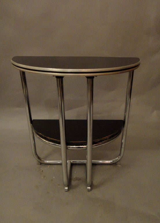 Console table half round with four chrome legs and round feet that support two black lacquered tops