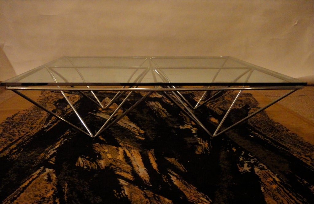 Coffee table with chromed steel bars that form a diamond pattern and support a square glass top