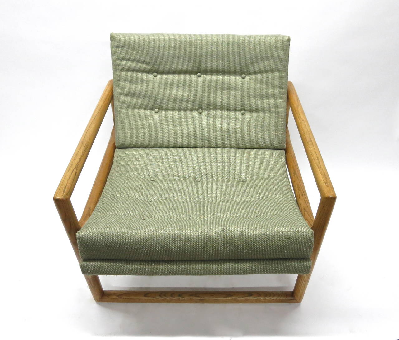 Vintage lounge chair with a rounded, solid oak frame that supports a newly upholstered seat in green and teal woven fabric. The wood has been refinished  and conditioned and maintains its natural aging.
