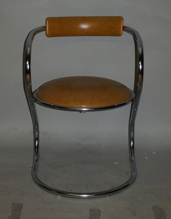 Desk chair with a round seat in leather that is supported by tubular chrome appears to be floating. The tubular frame continues to supports a back that is also done in the same leather.