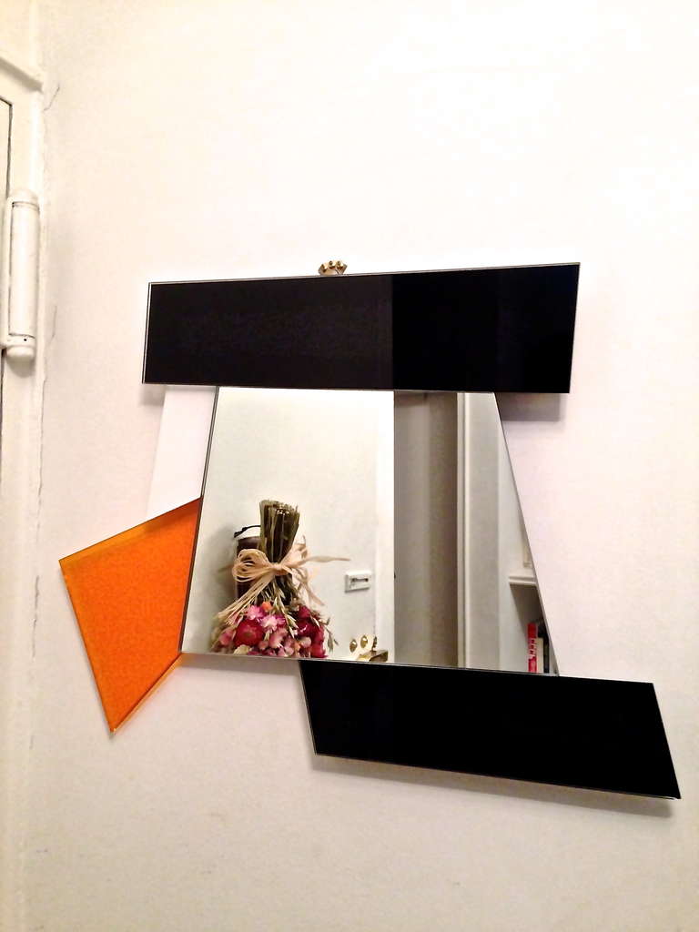 Dioniso four mirror of early production designed by Ettore Sottsass for Glas Italia in 2007 comprises orange, white, and black colored glass in geometric shapes that surround the central mirror and form this wall hanging art.