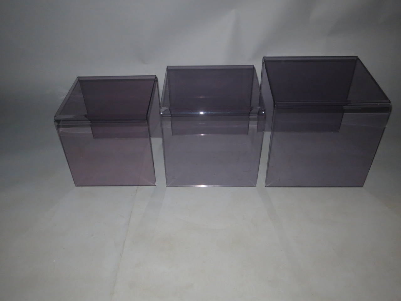 Three nesting tables in tinted Lucite. The color is what makes these original seamless table hard to find. This set is a 1960s production in near perfect condition. 
The smallest table measures 14 tall 13 3/4 wide and 13 3/4 deep.
The middle table