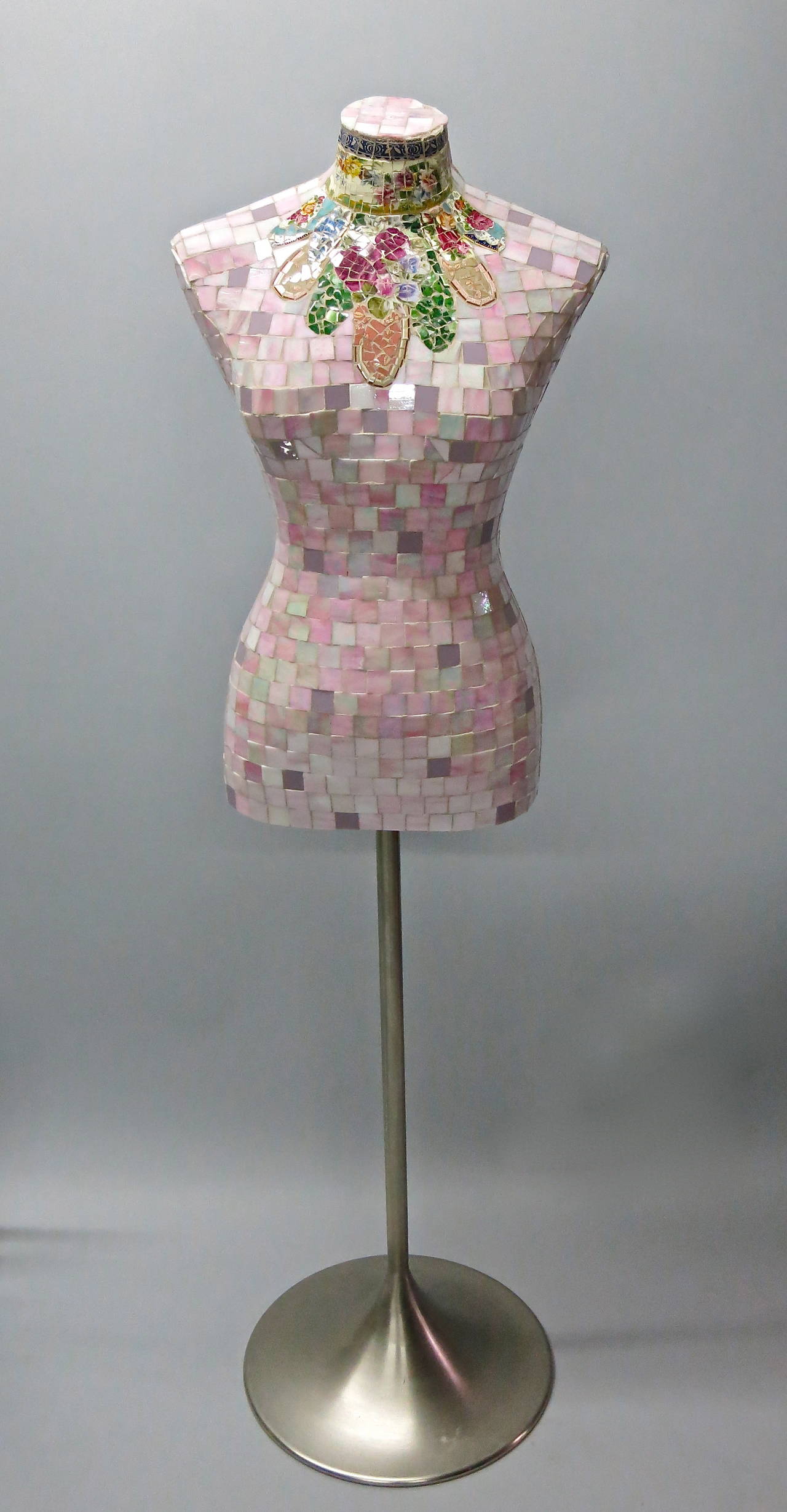Colorful tiled sculpture with a brushed steel pedestal base has over 1000 ceramic tiles in pink and purple tone that form a female torso supported on a tulip base in brushed steel.