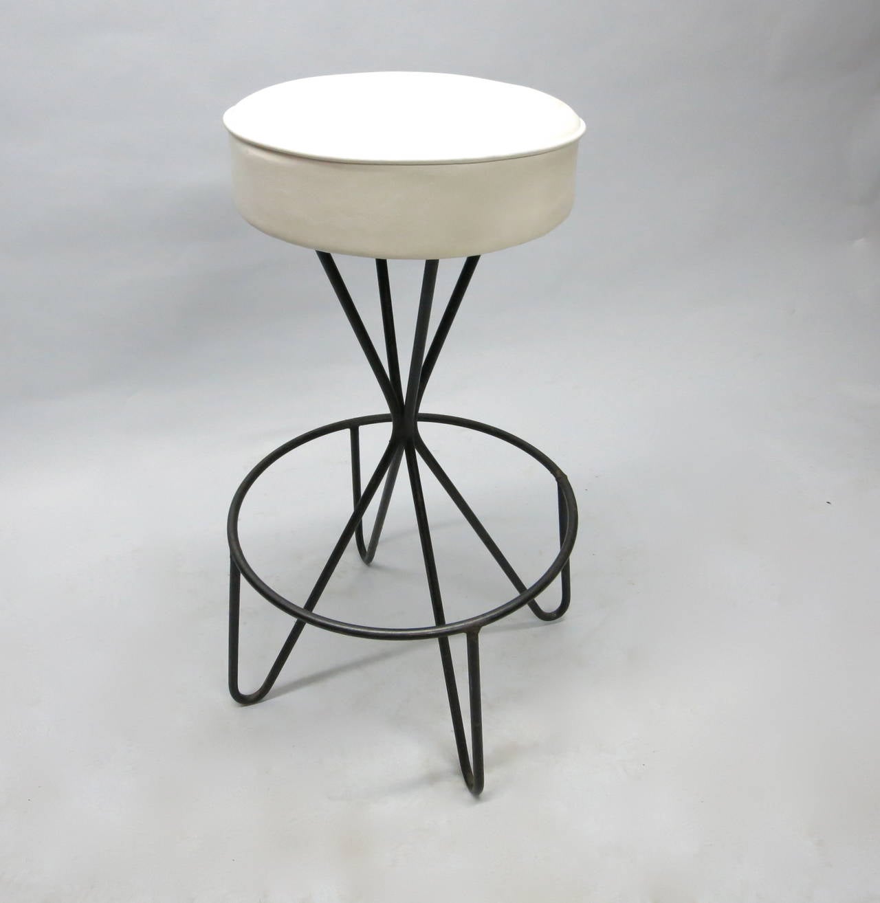 Eight stools with black tubular steel frame, four feet and a round foot rest. The frame supports a 4