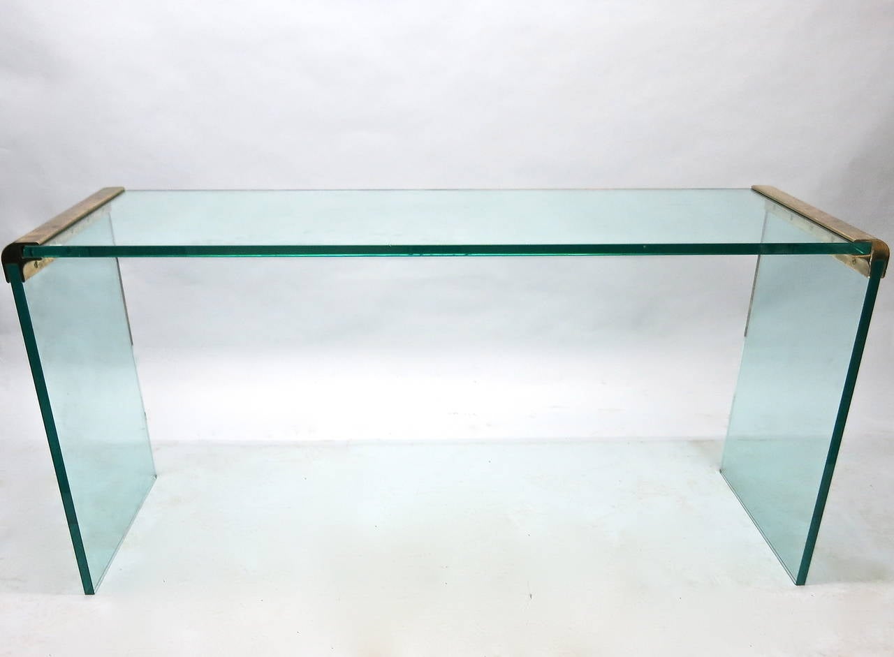 Sofa table has 3/4 inch glass that is supported by rounded waterfall edges made of patinated brass. The height is more appropriate as a sofa table but can also be used as a console.