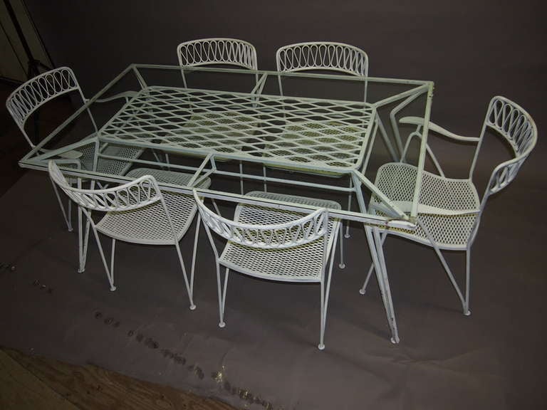 Dining set comprises a rectangular table with a glass top and six chairs, two arm and four armless. The table has a center detail of crisscrossing metal beneath the glass.
The set is in very good original condition with no damages.
Additional