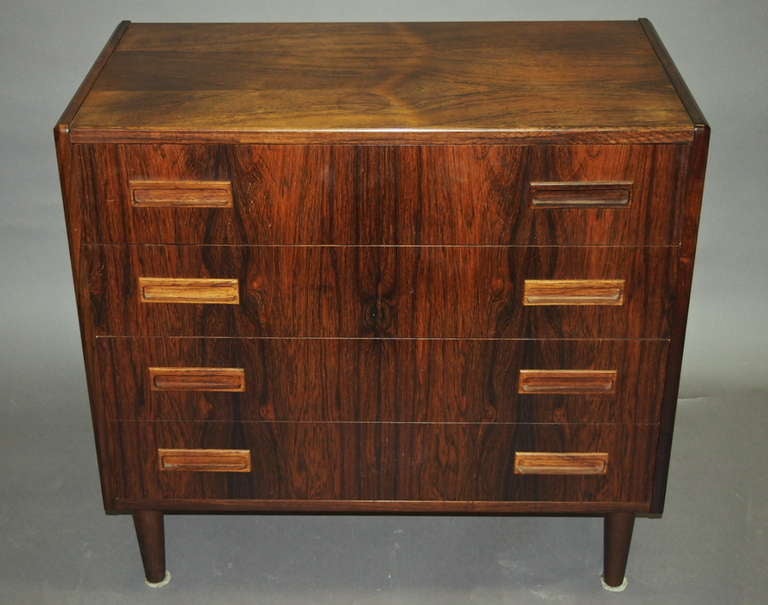 Cabinet or small dresser has four drawers on tapered legs all in rosewood and designed in the 1960's by Westergaard and also manufactured by Westergaard Mobelfabrik who produced Danish modern in the 60's