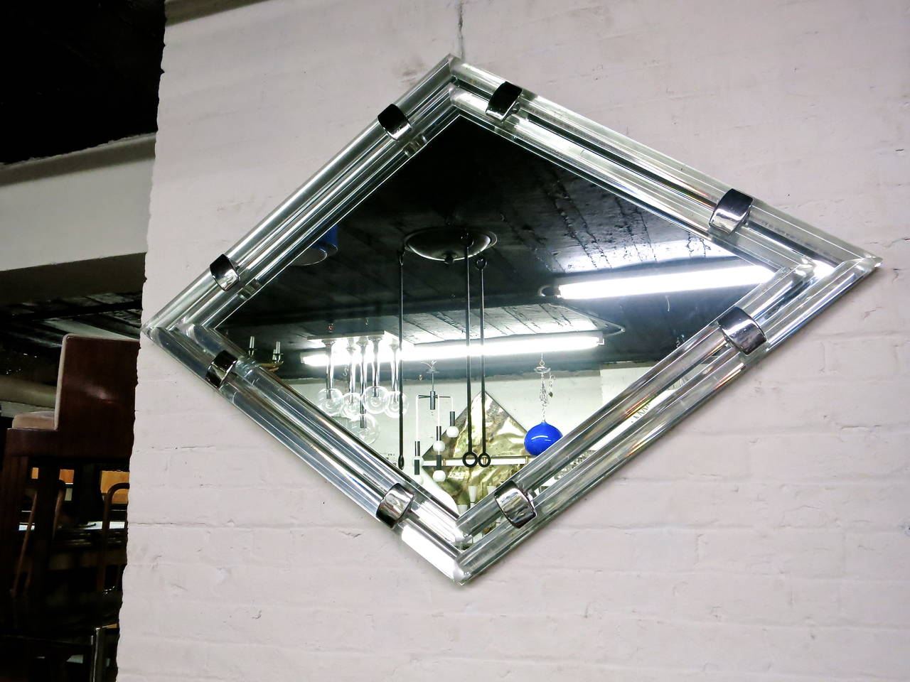 Well designed mirror bordered with parallel cylindrical Lucite that is mitered at all four points and secured by two polished steel hardware supports along each edge that come through the glass and secure the round Lucite without any pressure on the