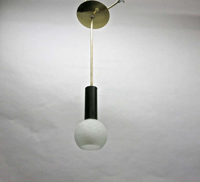 Three pendants with round crackled glass balls each with a single socket attached to a black enameled metal cylinder that covers the hardware and hangs from a single white wire with a metal canopy at the top. The pendants can hang at any length.