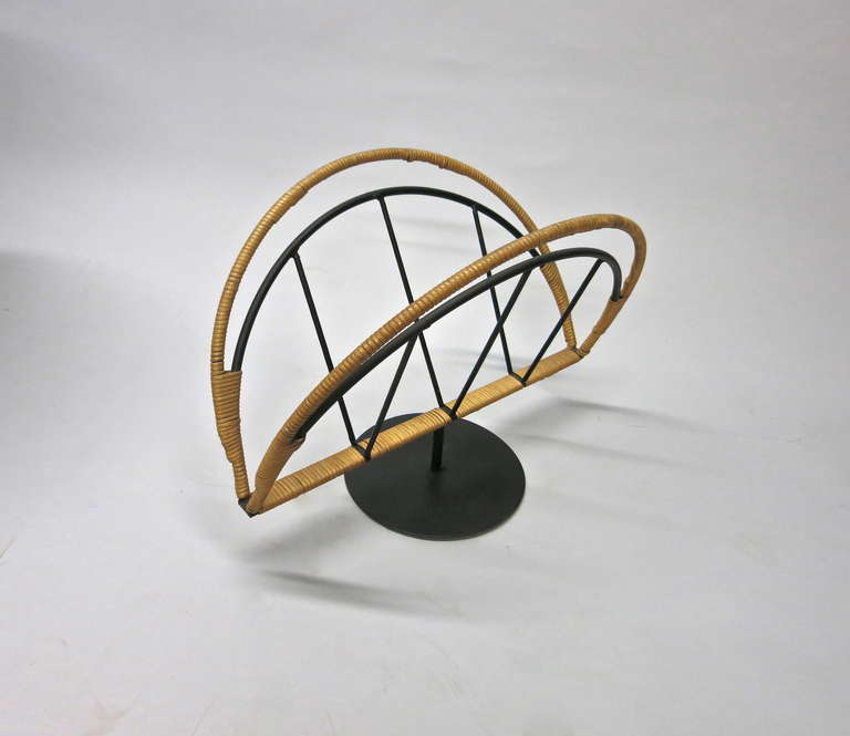 Magazine stand in black enameled metal partly wrapped in bamboo and supported by a round base with a tubular stem.