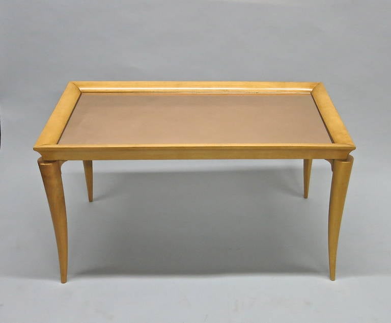 Coffee table with four arched tapered legs that support a floating frame, all in carved Sycamore that holds an inset top made of rose mirrored glass.