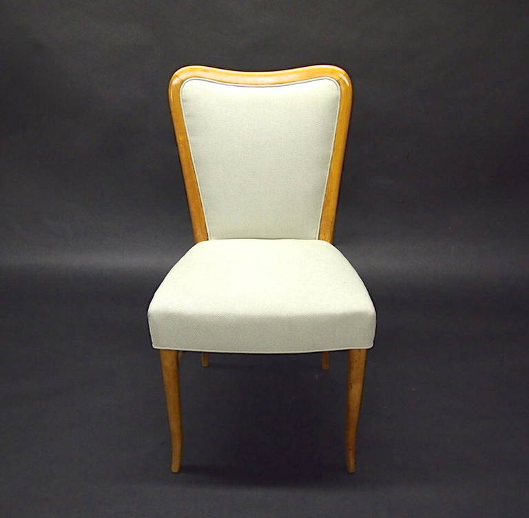 Blonde wood chair with four tapered arched legs with stretchers on each side. Has been recently upholstered in a vintage off-white woven fabric.