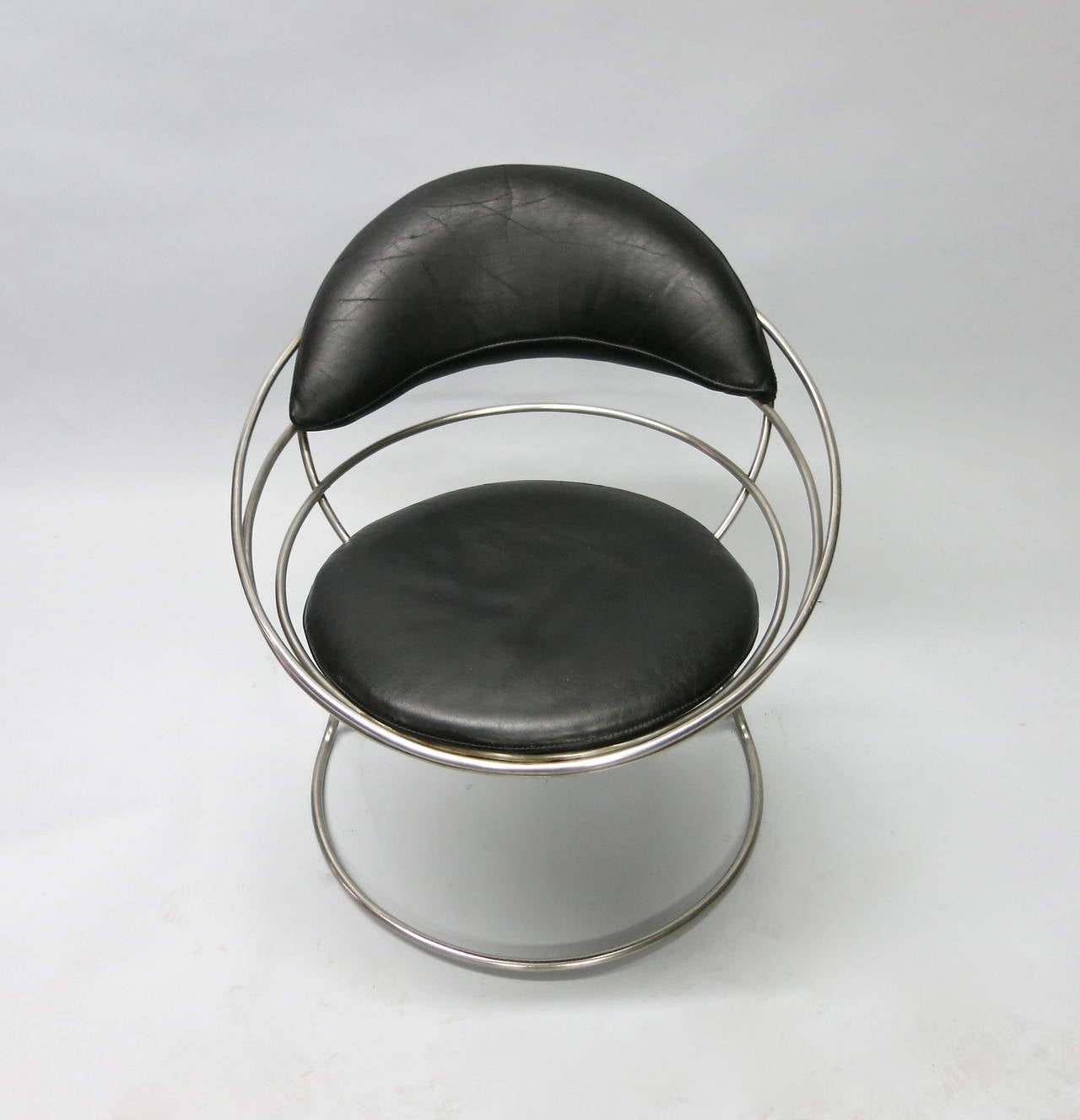 Chair with a tubular base and spiral frame that supports a black leather seat and back cushion. The 1960 original chair was designed and fabricated in France.