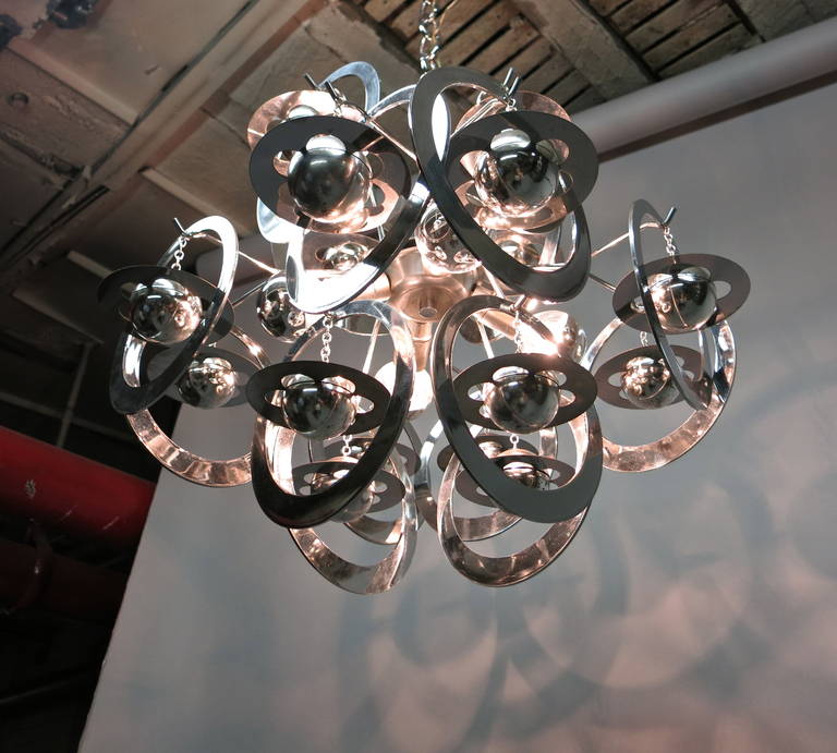 Bi-level ceiling lights that can rotate, each having 12 hanging ornamental objects in the shape of planets with four center sockets that have been rewired from European to American with candelabra sockets that can handle 60 watts in each.