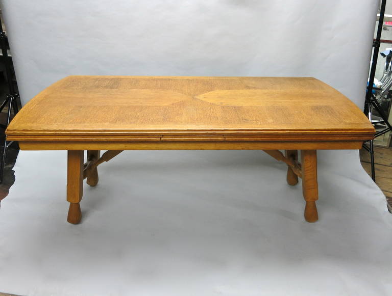 Strong dining table with a detailed oak top that has hand-carved, rounded and routed edges on all sides and two leaves that slide underneath the top. Each end of the top and the two leaves are arched; this creates a smooth continuation in wood grain