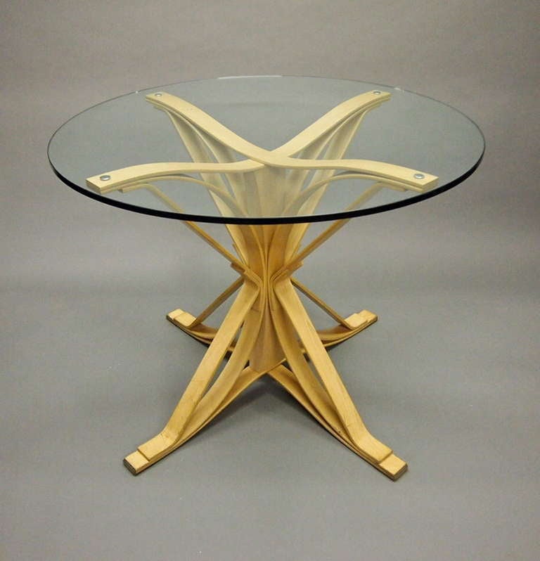 Dining Table designed in 1992 by Gehry was manufactured by Knoll in 1994 in maple wood and has a 36 inch round glass top.