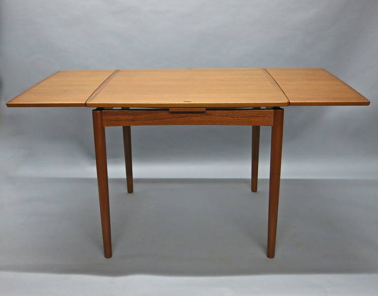 Extending dining table with a reversible top for games the teak side extends on each end to seat six for dining.