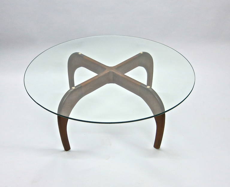 Coffee table in walnut designed by Adrian Pearsall for Craft Associates in the 1960's with four symmetrical legs that cross in the center and support a round beveled edge glass top. The table is in great original condition.