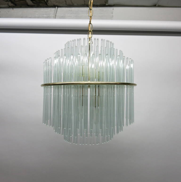 Ceiling light made of glass rods that are supported by a brass-plated, center frame and create three cascading tiers on the top and bottom that diffuse light shone from four middle sockets.