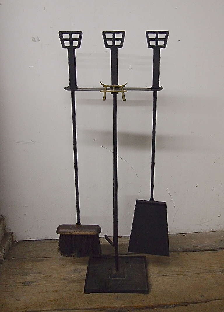 Set of fire tools with a wrought iron stand that holds a poker shovel, broom and  solid brass detail of an oriental character all in original vintage condition