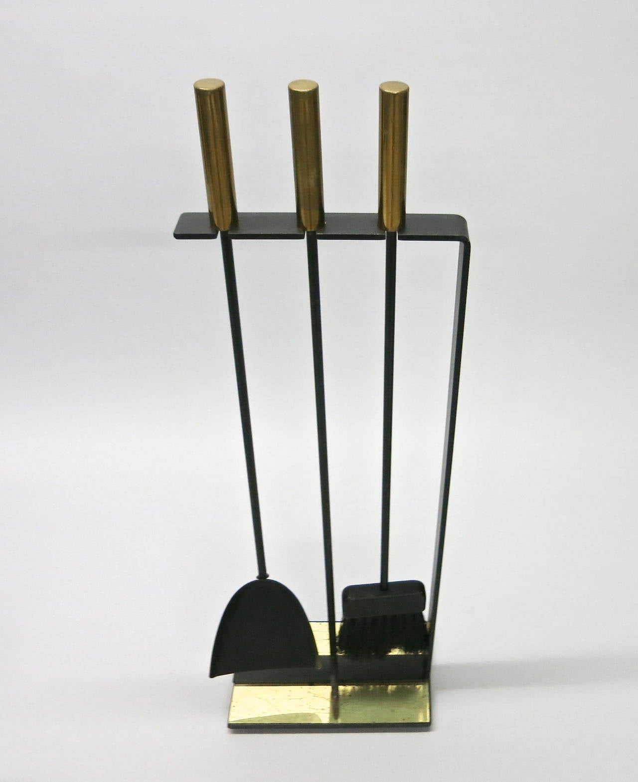 Set of fire tools with a poker, broom and shovel in black wrought iron with patinated brass handles and and a plated brass detail not the base.