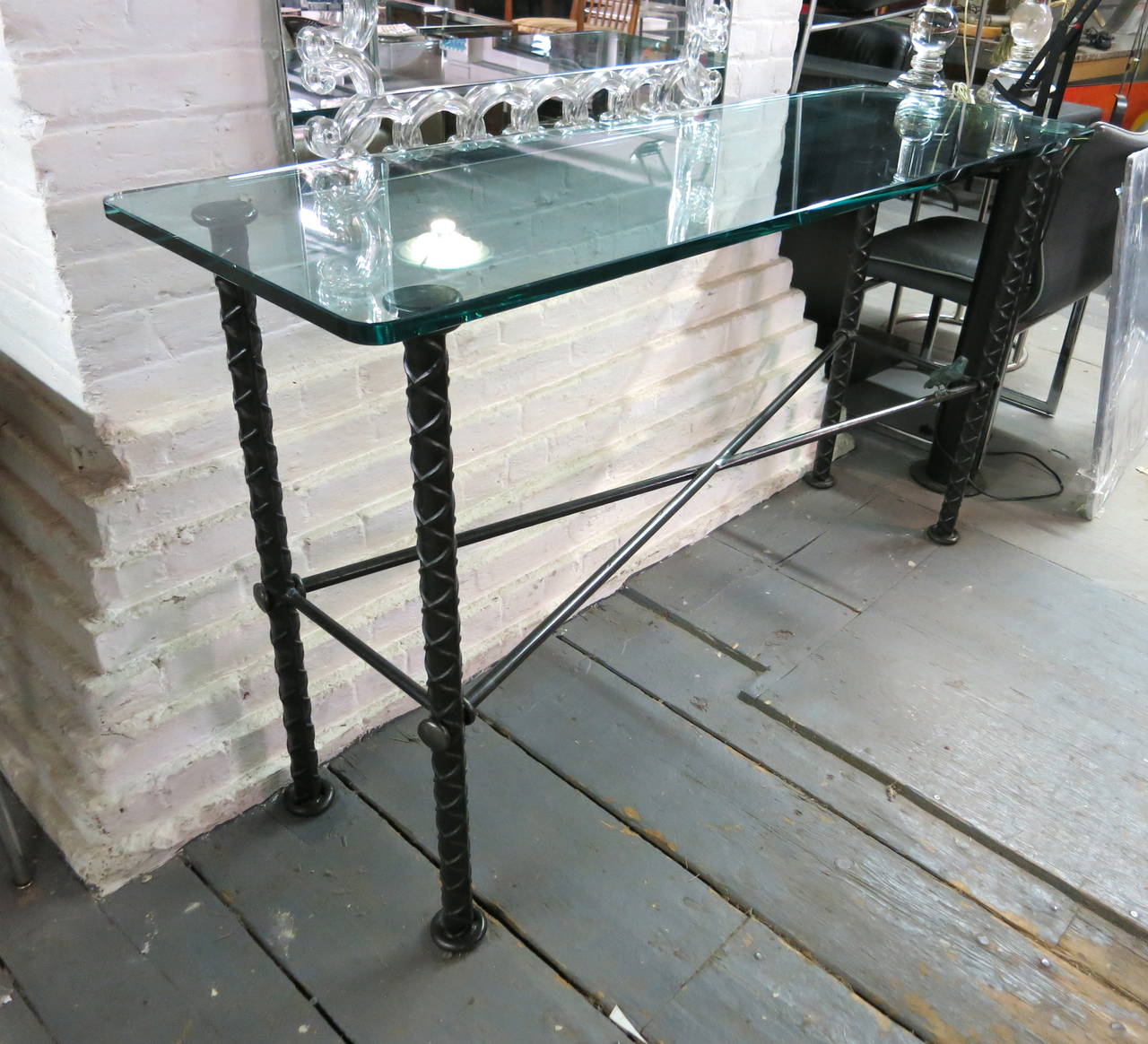 Console Table has a glass top supported by four legs connected by an X shaped stretcher that holds a figure of a bird.