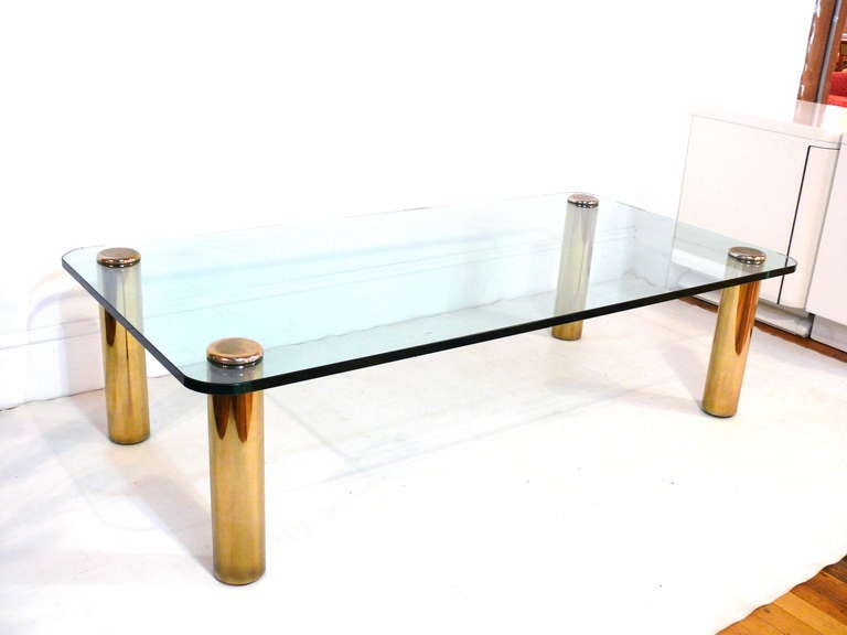 Brass and glass coffee table by Pace @ 1970's.  Brass capped legs support a radius edged glass top.