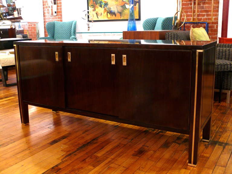 Very unique American credenza with brass accents and hardware.  The credenza has plenty of storage including a deep file drawer. Brass accents are on the back as well which is also finished.